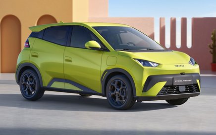 BYD Dolphin Surf Elektroauto in grün steht vor modernen Gebäuden in künstlicher Umgebung