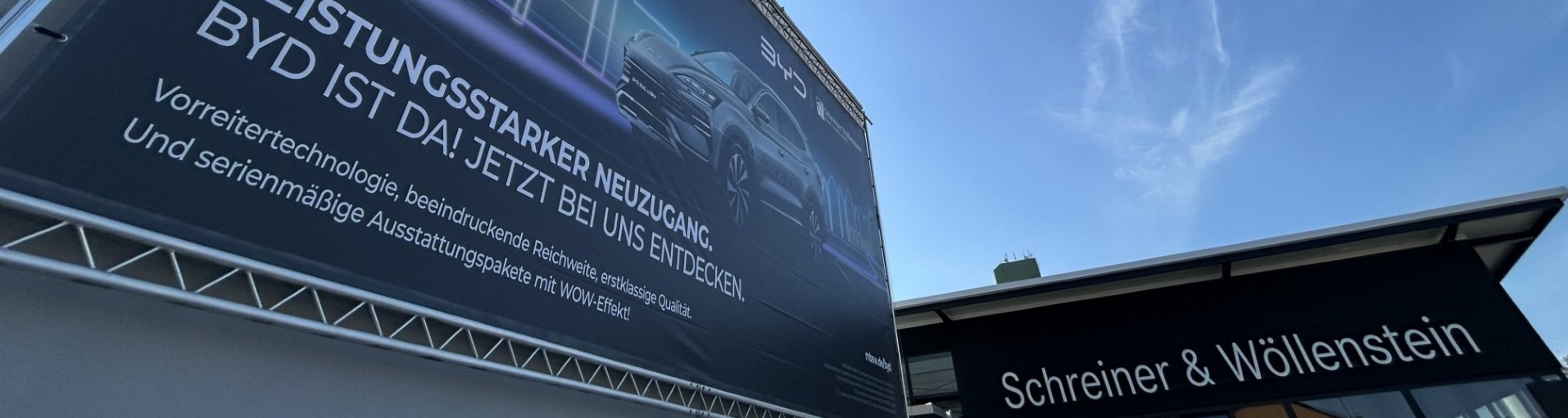 Plakat mit BYD-Thema vor Schreiner & Wöllenstein-Autohaus