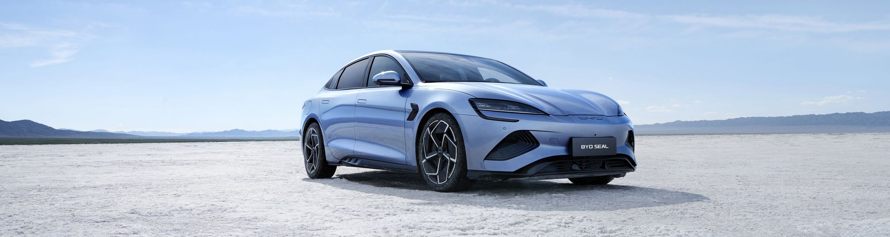 Blauer BYD SEAL Elektroauto steht auf weißem Salzsee unter blauem Himmel